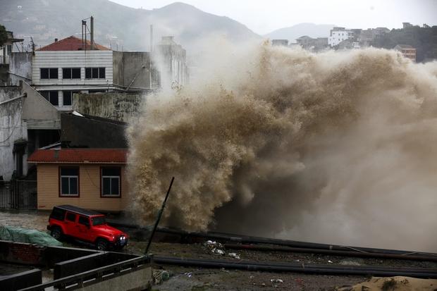 A huge wave whipped up by Typhoon Chan Hom hits the shore as a vehicle passes by in Wenling in Zhejiang province in eastern China