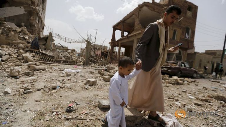 A man and a boy walk at a site hit by a Saudi-led air strike in Yemen's capital