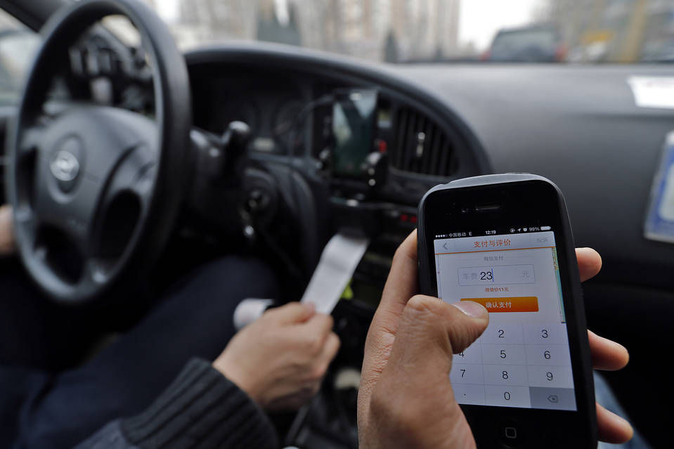 A passenger uses the Didi Kuaidi app to pay for taxi fare in this undated