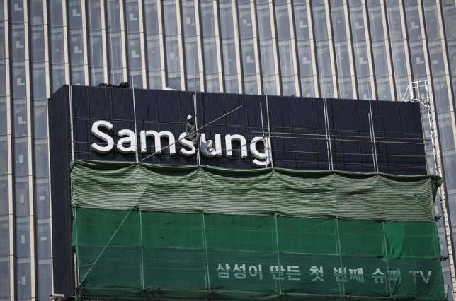 A worker works on a Samsung outdoor advertisement installed atop an office building in central Seoul