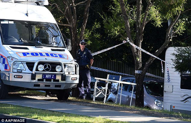 A police officer standing outside a house in which the body of a young boy was found in Brisbane's south