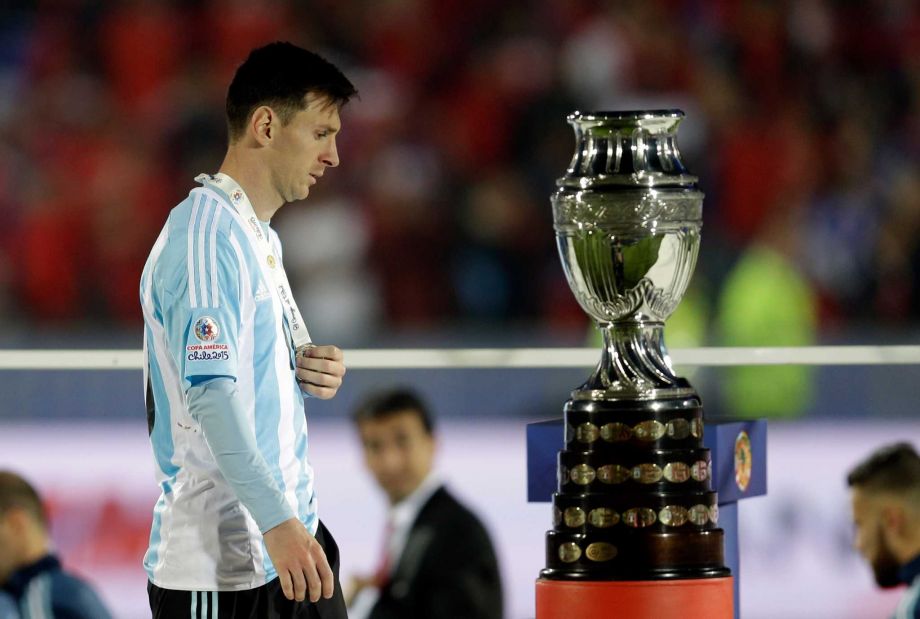 Argentina's Lionel Messi walks by the Copa America trophy after receiving the silver medal after the final game with Chile at the National Stadium in Santiago Chile Saturday