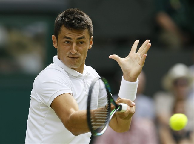 Bernard Tomic of Australia returns a ball to Novak Djokovic of Serbia during their singles match at the All England Lawn Tennis Championships in Wimbledon London Friday