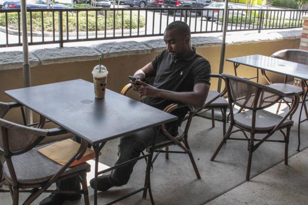 Gordon sits outside a Starbucks after being served with papers on Sunday. The suit claimed he caused Brown'substantial harm including one occasion when he knocked her tooth out and dragged her upstairs by her hair