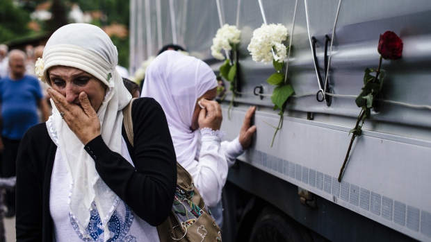 Bosnian Muslim women reacts as they touch a truck carrying 136 coffins of newly identified victims of the 1995 Srebrenica massacre in the town of Visoko near Sarajevo on Thursday