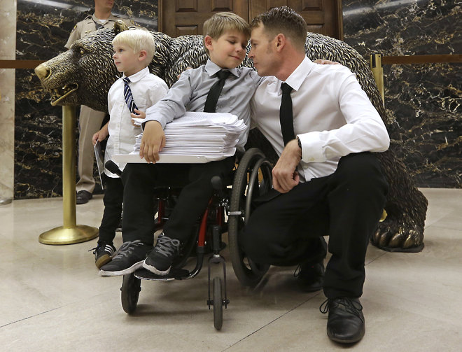 Otto Coleman 6 waits outside the Governor's office with his brother Fenton 4 left and father Joshua to deliver a stack of petitions with thousands of signatures calling on California Gov. Jerry Brown to veto a measure requiring nearly all California