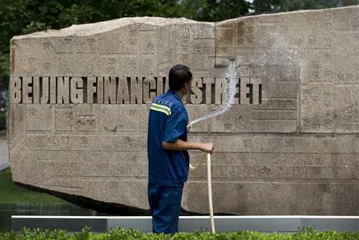 Beijing financial street A cleaner sprays water to clean a name plague on display outside an office building at the Financial Street of Beijing Wednesday