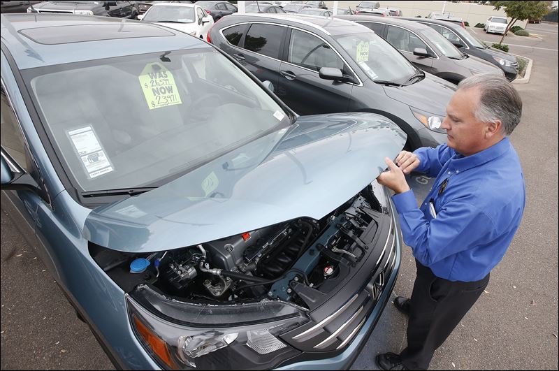 Mike Johnson a sales manager at a Honda car dealership opens the hood of a Honda CRV SUV in Tempe Ariz