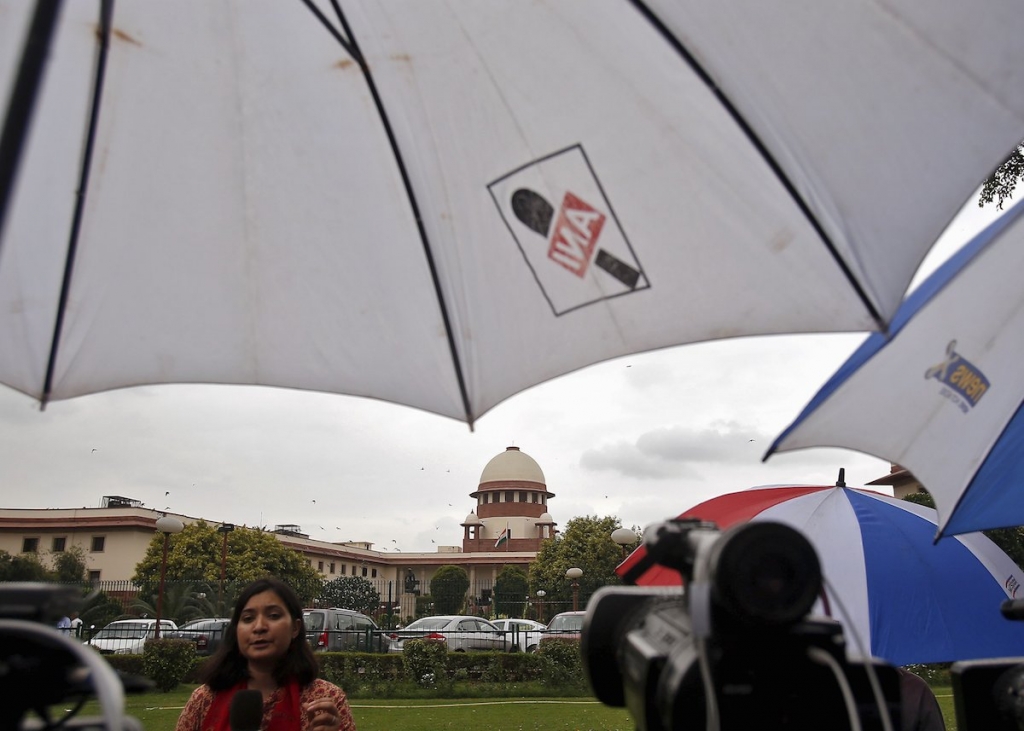 A television journalist reports from the premises of the Supreme Court as it rains in New Delhi India yesterday. India's Supreme Court dismissed a final appeal for mercy by the only person to be sentenced to death for a series of bombings in Mumbai in 1