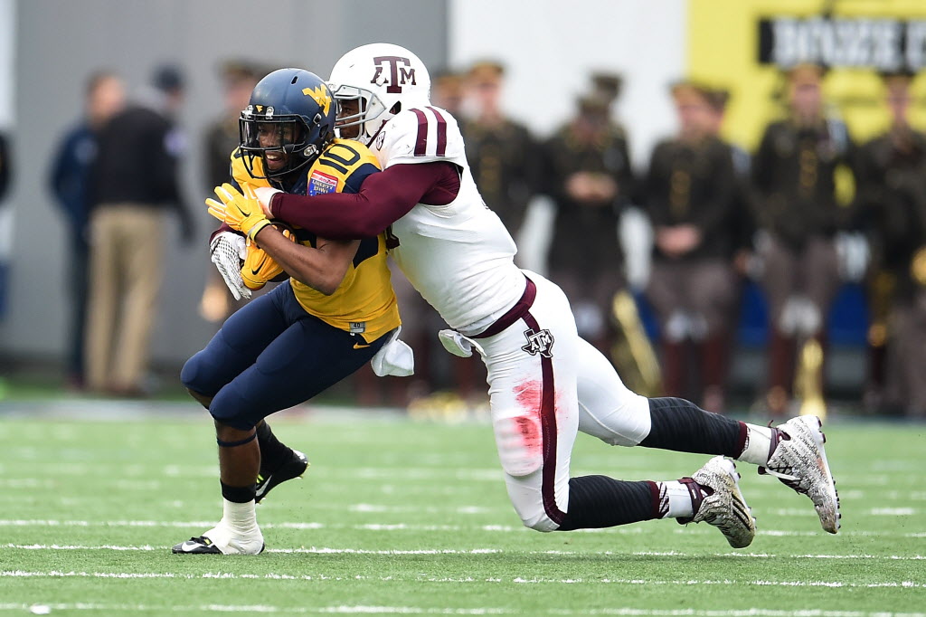 MEMPHIS TN- DECEMBER 29 Jordan Thompson #10 of the West Virginia Mountaineers is brought down by Myles Garrett #15 of the Texas A&M Aggies during the second quarter of the 56th annual Autozone Liberty Bowl at Liberty Bowl Memorial Stadium on December 2