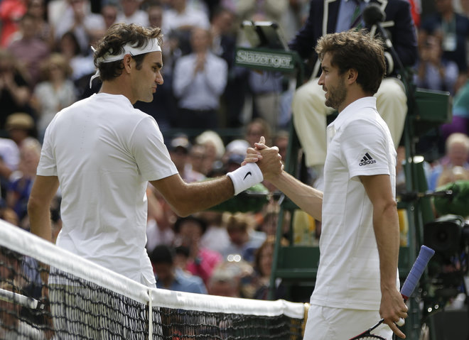 Roger Federer of Switzerland left shakes hands at the net with Gilles Simon of France after winning their quarterfinal singles match at the All England Lawn Tennis Championships in Wimbledon London Wednesday