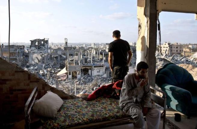 Gaza men sit in their apartment building destroyed during the 2014 war between Hamas and Israel