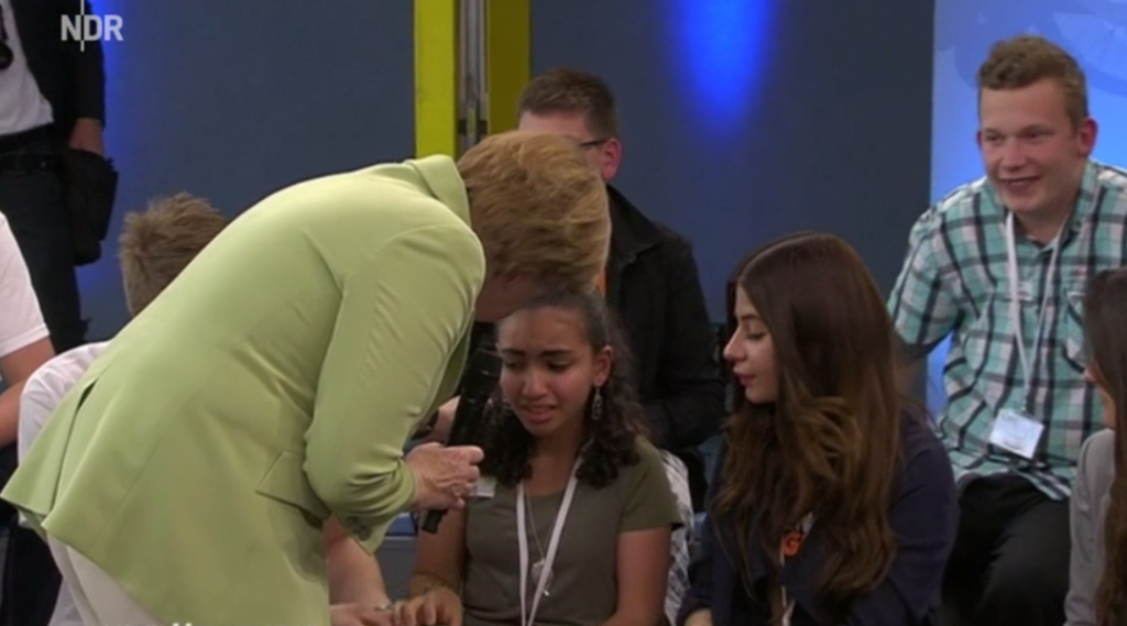 German Chancellor Angela Merkel attempts to comfort a young refugee named Reem who is facing deportation