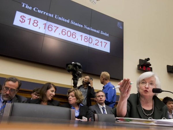 Federal Reserve Chair Janet Yellen sits under a current US national debt chart as she testifies on Capitol Hill in Washington Wednesday