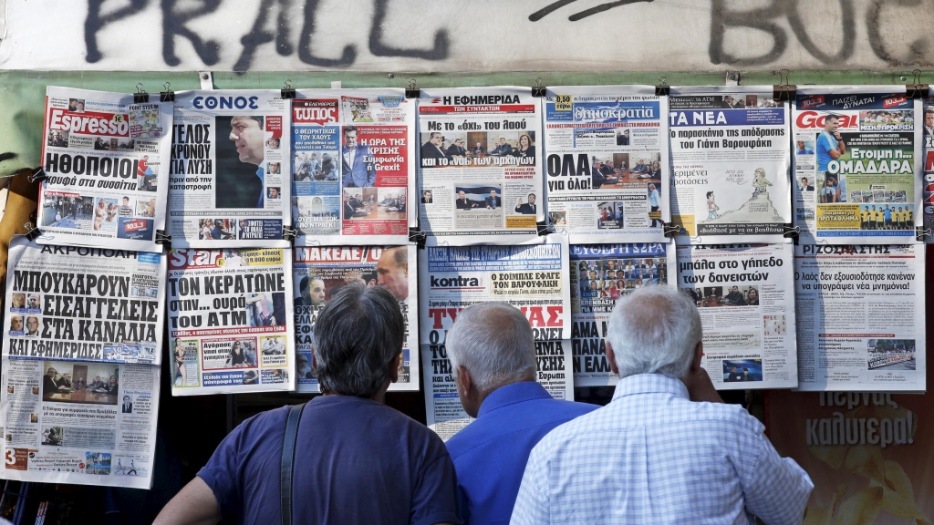 People read the front pages of various newspapers hanging at a kiosk Tuesday in central Athens. European leaders have set a Sunday deadline for Greece to reach a deal on debt repayment and austerity measures