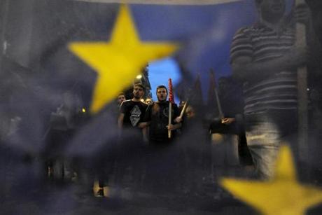 Anti-EU protesters were seen through a burned and torn European Union flag during a protest at the northern city of Thessaloniki on Wednesday