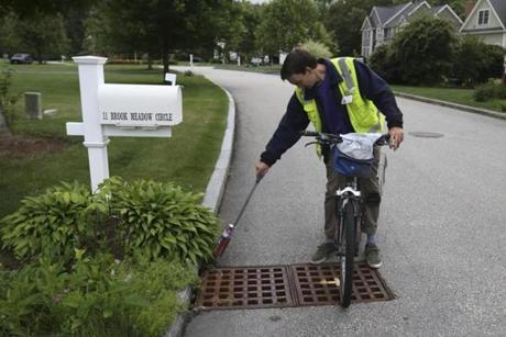 Joe Sandore paints the corner of a drain with chemical larvasides in Framingham