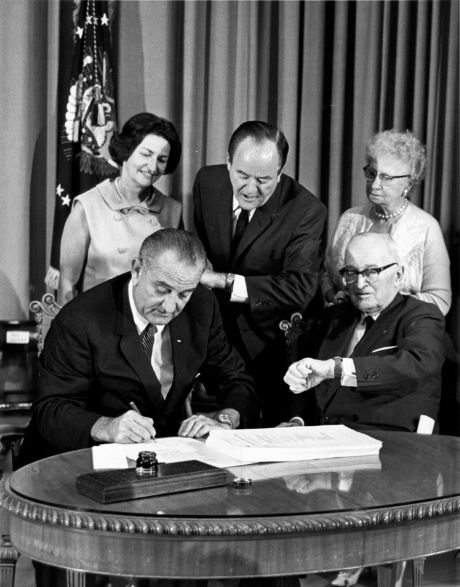 President Lyndon B. Johnson left signs the Medicare Bill a signature piece of legislation that he touted as a'blessing for older Americans.'﻿  Associated Press