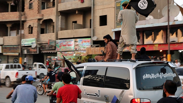 ISIS supporters wave the group's flags as they drive around Al Raqqa in north-central Syria in June 2014