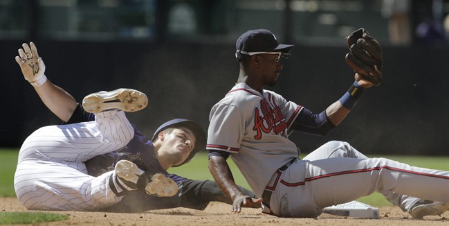 Colorado Rockies baserunner Nolan Arenado left slides safely into second base on a double against Atlanta Braves second baseman Pedro Ciriaco right in the fifth inning of a baseball game in Denver Saturday