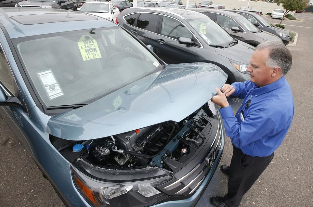 Mike Johnson a sales manager at a Honda car dealership opens the hood of a Honda CRV SUV in Tempe Ariz. Automakers release vehicle sales for June 2015 on Wednesday