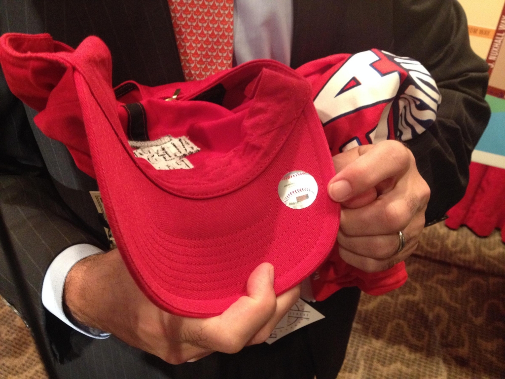 MLB's Ethan Orlinsky holds up a licensed hat with a hologram and an unlicensed t-shirt that does not have