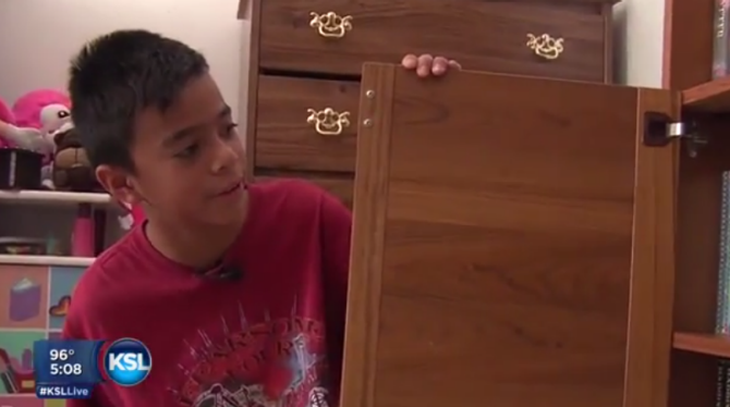 Matthew Flores showing off his bookcase now filled with books.   		KSL