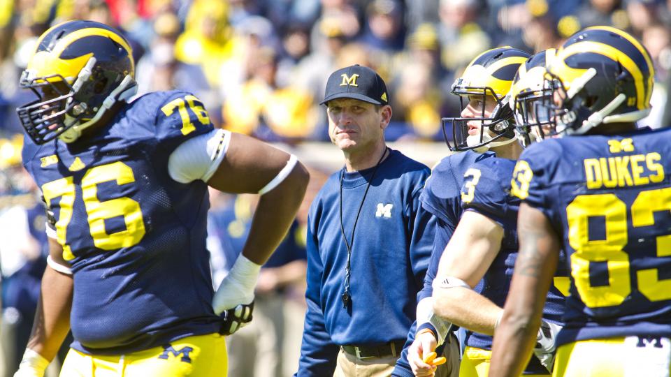 Michigan head coach Jim Harbaugh stands on the field amongst his players between downs during the NCAA college football team's spring game in Ann Arbor Mich. Saturday