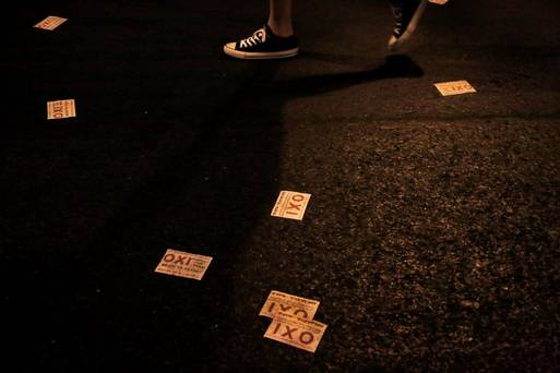 A demonstrator walks along a road with leaflets reading 'no&#039 scattered on the ground following a demonstration supporting the no vote on the upcoming referendum outside of the European Union office in central Athens on Thursday