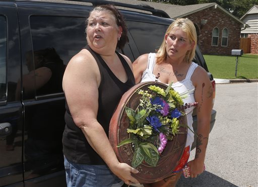 Cindy Rigney left and Glenna Parkman right who live in Broken Arrow arrive with a wreath outside of a home in Broken Arrow Okla. Thursday