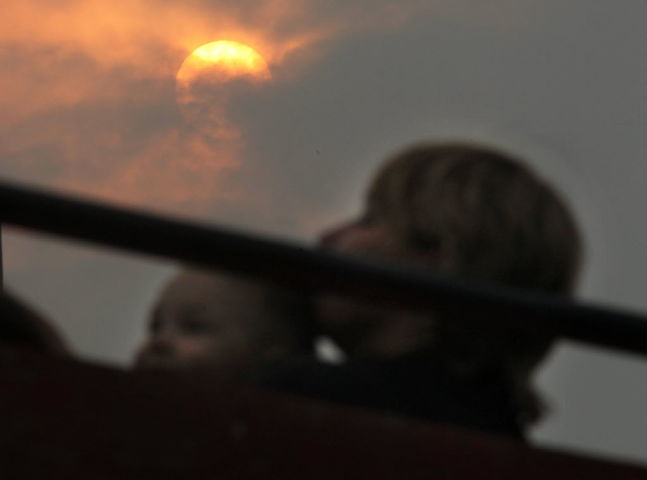 The setting sun blazes orange through a thick haze of smoke as baseball fans take in a game Tuesday evening at Andrews Field. Hundreds of forest fires raging in northern Alberta and Saskatchewan have left a gigantic plume of smoke drifting throughout wes