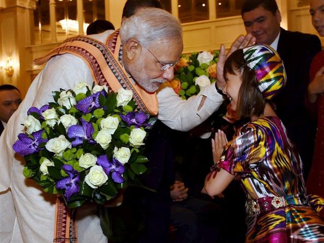 Prime Minister Narendra Modi is greeted by a child during his meeting with Indian community members in Tashkent on Tuesday