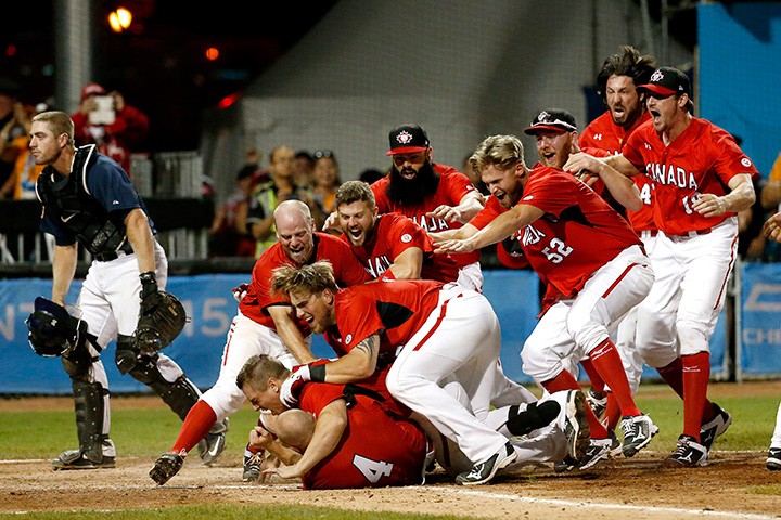 Team Canada players mob Peter Orr after he scored the game-winning run against the United States in the 10th inning of the gold medal baseball game at the Pan Am Games Sunday