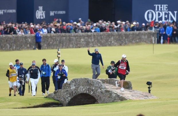 Paul Dunne a 22-year-old amateur from Dublin takes some well-earned applause as he heads over the Swilcan Bridge