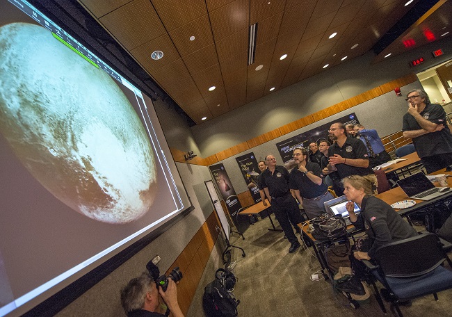 Members of the New Horizons science team react to seeing the spacecraft’s latest image of Pluto prior to its approach Tuesday