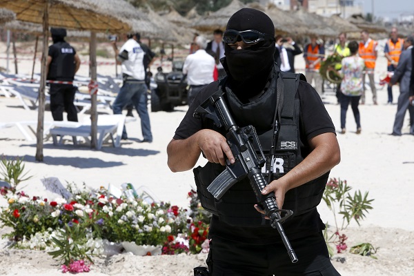 A hooded Tunisian police officer stands guard ahead of the visit of top security officials of Britain France Germany and Belgium at the scene of Friday's shooting attack in front of the Imperial Marhaba hotel in the Mediterranean resort of Sousse