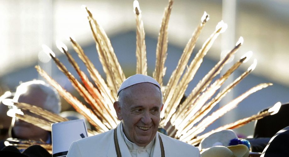 Pope Francis is framed by a feather headdress worn by one of the indigenous people and children wearing traditional costumes greeting him upon his arrival at the El Alto airport Bolivia Wednesday