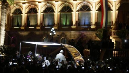 Pope Francis stands in his popemobile as he is driven away from the Lopez Presidential Palace in Asuncion Paraguay