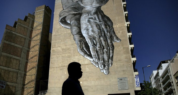 A pedestrian walks through empty streets by a mural in Athens Greece