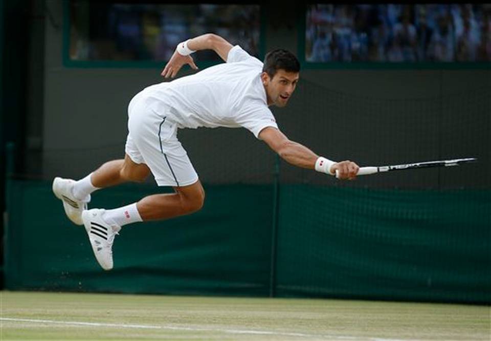 Novak Djokovic of Serbia jumps to return a ball to Kevin Anderson of South Africa during their singles match against at the All England Lawn Tennis Championships in Wimbledon London Tuesday