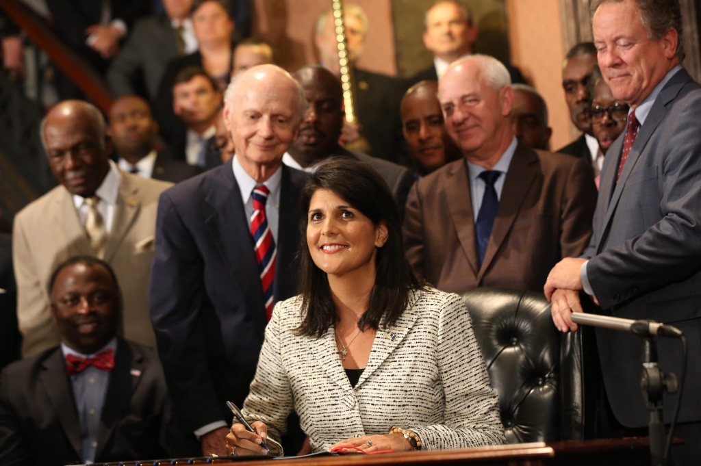 With her predecessors in the governor's office and others looking on Gov. Nikki Haley signs into law a bill that removes the Confederate flag from the State House in Columbia