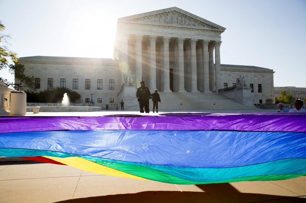 Gay marriage supporters hold a gay rights flag in front of the U.S. Supreme Court before a hearing about gay marriage