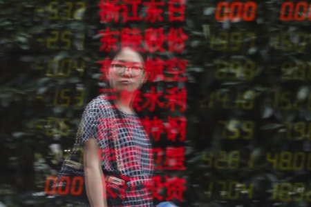 A woman is reflected on an electronic board showing stock information at a brokerage house in Shanghai China