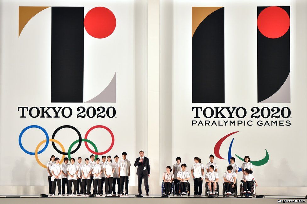 Hammer throw gold medallist Koji Murofushi, accompanied by young athletes delivers a speech as the logo marks of the Tokyo 2020 Olympic and Paralympic Games are unveiled at the Tokyo city hall on 24 July 2015