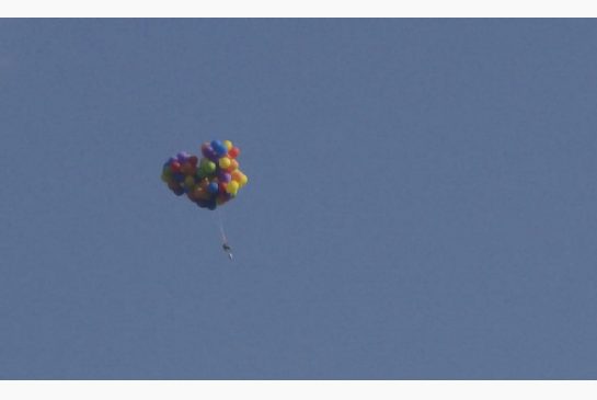 Daniel Boria flies a lawn chair suspended on balloons near the Calgary Stampede grounds