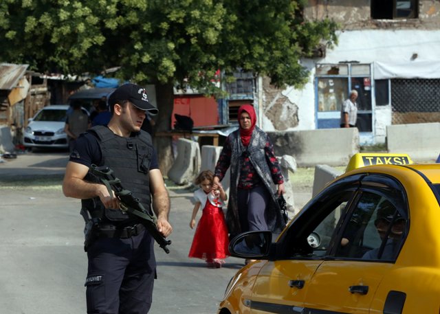 A police officer checks IDs as Turkish police raid homes in the Haci Bayram neighborhood of the capital Ankara Turkey Monday