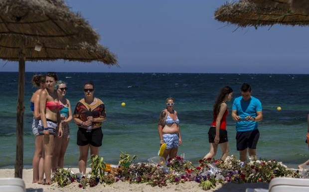 Tourists pay their respects in front of flowers laid out along a beachside in memory of the victims killed by a gunman at the Imperial Marhaba resort in Sousse Tunisia