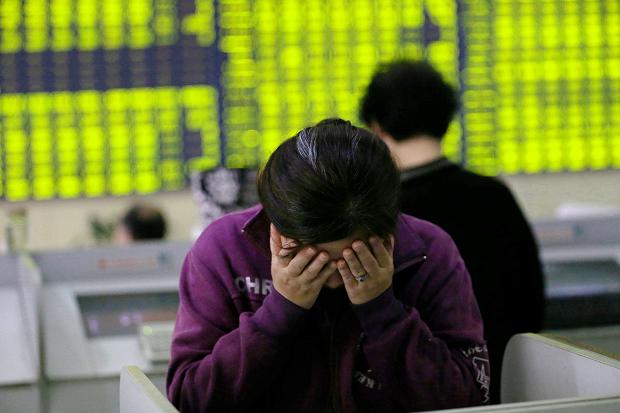 Concerned Chinese investors look at prices of shares at a stock brokerage house in Nantong city