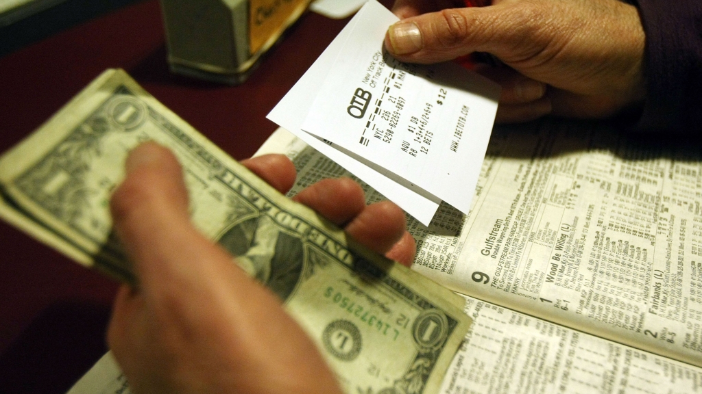 A man holds his betting slips and money at a betting parlor