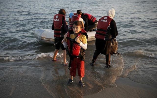 A migrant boy removes his lifejacket moments after arriving on a dinghy with his family on the Greek island of Kos